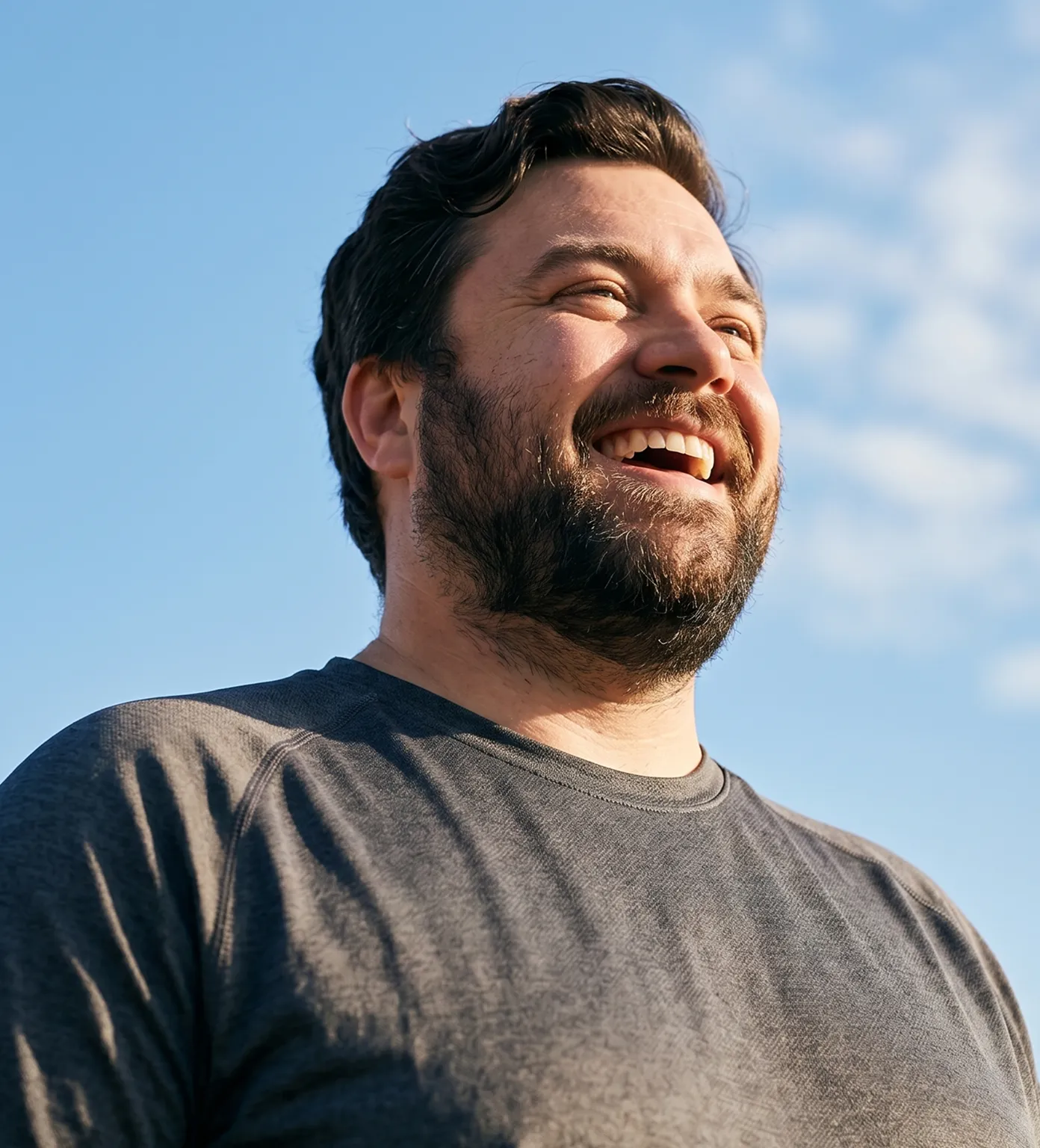 Lachender Mann im Freien vor blauem Himmel
